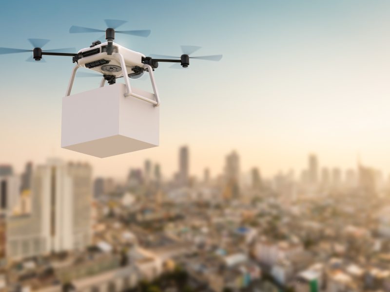 Drohne fliegt mit Paket über die Stadt